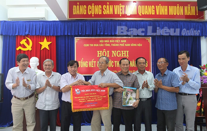 Nhà báo Nguyễn Duy Hoàng, Chủ tịch Hội Nhà báo Việt Nam tỉnh Bạc Liêu - Cụm trưởng năm 2018 (thứ ba từ trái sang) trao cờ Cụm trưởng năm 2019 cho Hội Nhà báo tỉnh Sóc Trăng. Ảnh: H.T