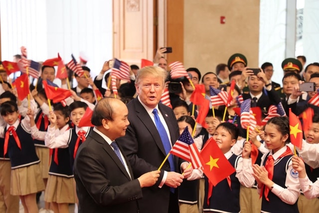 Thủ tướng Nguyễn Xuân Phúc cùng thành viên Chính phủ và các em thiếu nhi chào mừng Tổng thống Mỹ. Ảnh: VnEconomy