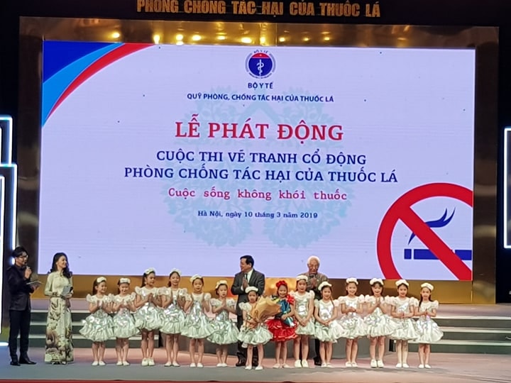 PGS, TS. Lương Ngọc Khuê - Cục trưởng Cục Quản lý Khám - chữa bệnh (Bộ Y tế), Giám đốc Quỹ Phòng, chống tác hại của thuốc lá và họa sỹ Trần Khánh Chương - Chủ tịch Hội Mỹ thuật Việt Nam tặng hoa cho các cháu thiếu nhi. Ảnh: Báo KTNT