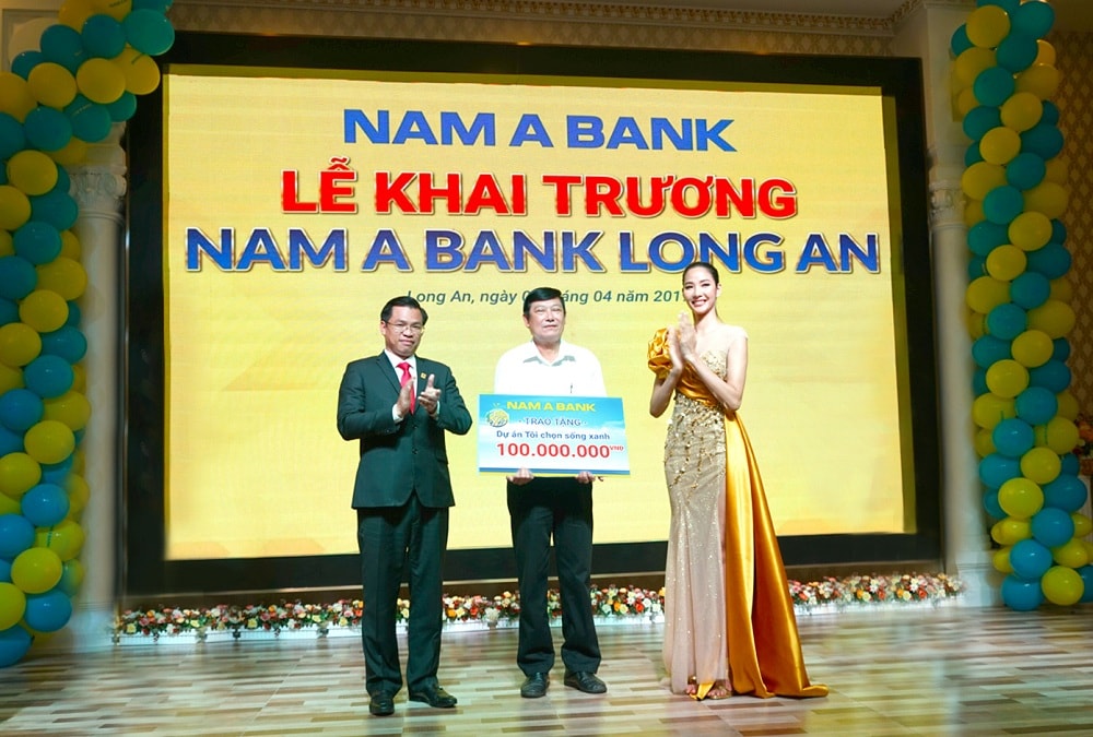 Ông Trần Ngọc Tâm - Tổng Giám đốc Nam A Bank cùng Á hậu Hoàng Thùy trao tặng bảng tượng trưng cam kết về việc triển khai hai dự án vì cộng đồng “Tôi chọn sống xanh” và “Nâng bước đến trường - Thắp sáng tương lai” cho ông Huỳnh Văn Nhịn - Phó Chủ tịch UBND TP. Tân An.