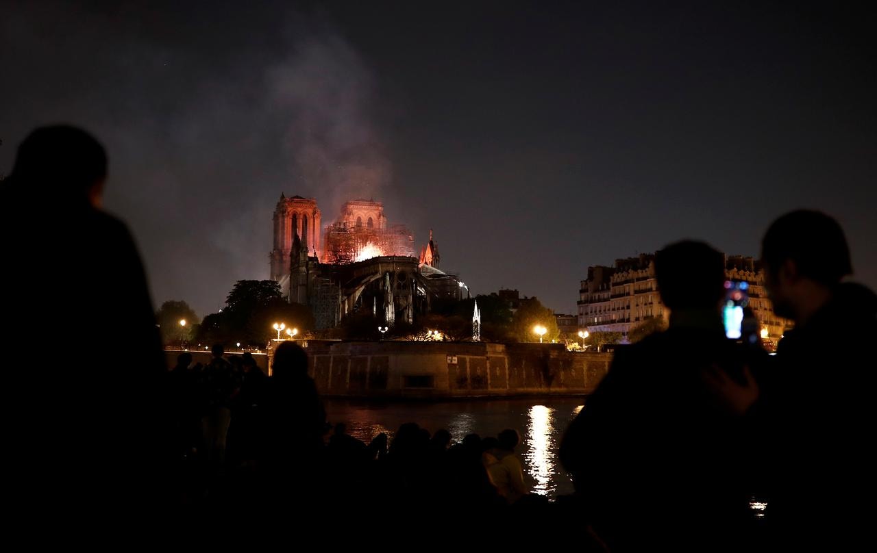 Người dân Paris đứng nhìn nhà thờ Notre-Dame bốc cháy từ phía xa. Ảnh: Reuters
