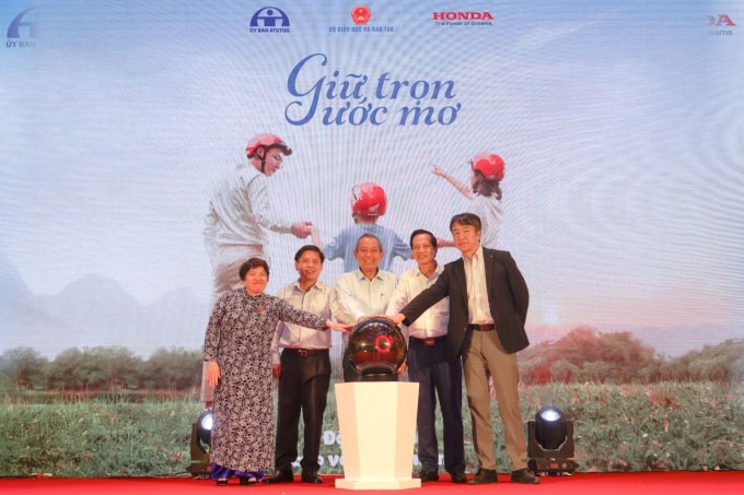 Phó Thủ tướng Trương Hòa Bình, Bộ trưởng Bộ GTVT Nguyễn Văn Thể và các đại biểu thực hiện nghi thức phát động chương trình trao tặng mũ bảo hiểm cho học sinh. Ảnh: TL