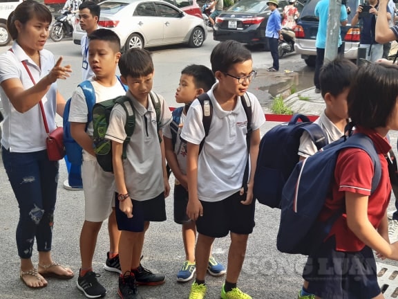 Học sinh sau khi xuống xe, xếp hàng theo sự chỉ đạo của giáo viên vào trường. Ảnh: Hùng Long