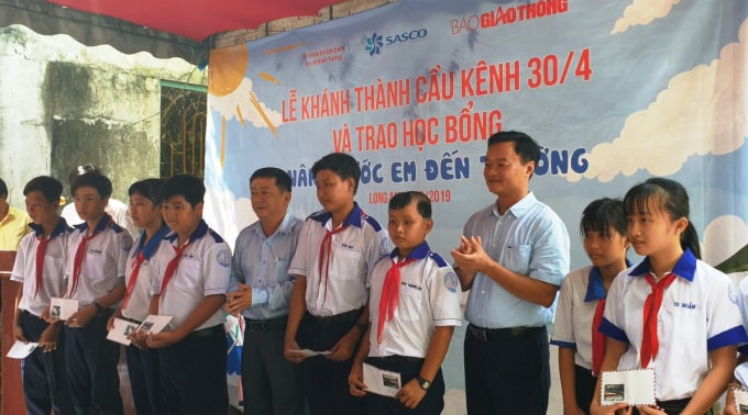 Ông Nguyễn Bá Kiên - Tổng biên tập Báo Giao thông và ông Nguyễn Quốc Trung, Phó giám đốc Sở GTVT tỉnh Long An trao 20 suất quà từ Quỹ chung tay vì ATGT của Báo Giao thông cho các em học sinh. Ảnh: baoggiaothong.vn