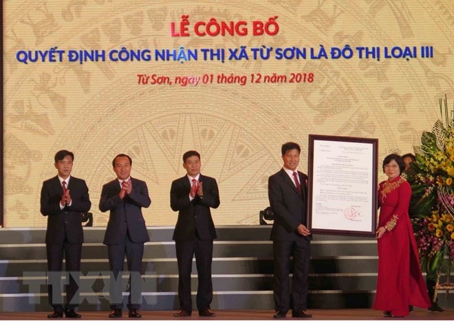 Thứ trưởng Bộ Xây dựng Phan Thị Mỹ Linh trao Quyết định của Bộ Xây dựng công nhận thị xã Từ Sơn là đô thị loại III cho lãnh đạo thị xã Từ Sơn. (Ảnh TTXVN)
