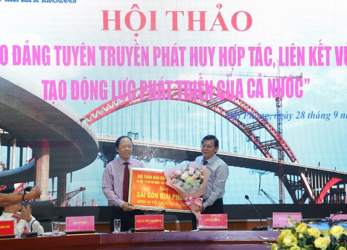 Nhà báo Lê Trọng Nghĩa (trái), Tổng Biên tập Báo Hải Phòng trao cờ luân lưu cho nhà báo Nguyễn Tấn Phong (phải), Tổng Biên tập Báo Sài Gòn Giải Phóng. Ảnh: Ánh Trần