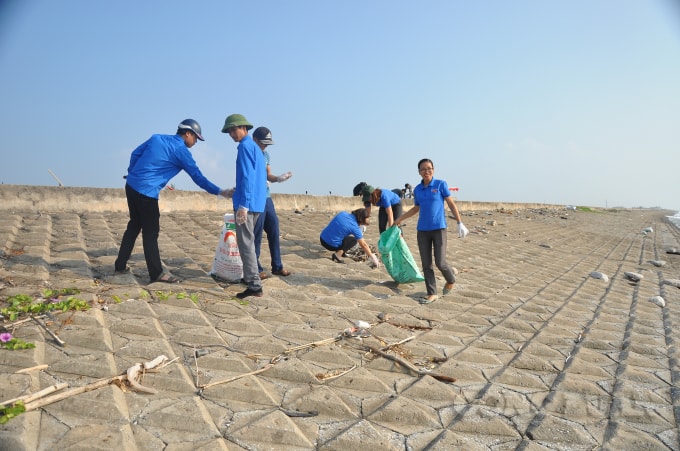 Đoàn viên thanh niên thị trấn Thịnh Long đi dọc tuyến đê biển thu gom rác thải. Ảnh: Mỹ Ngọc