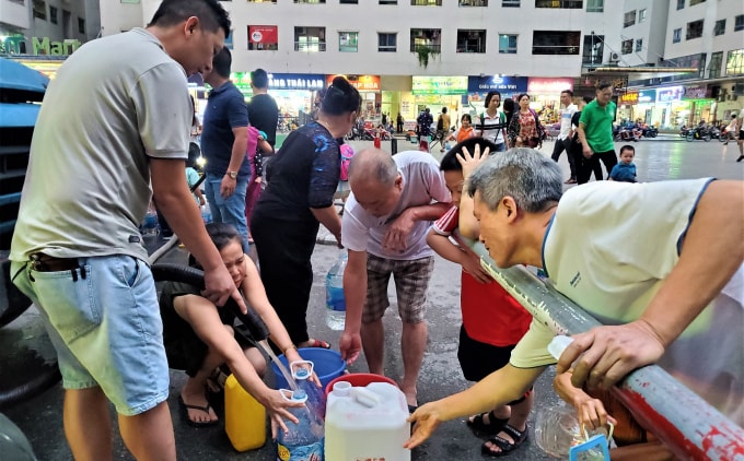 Người dân khu chung cư HH - Linh Đàm xếp hàng, chen chúc để lấy nước sạch như thời bao cấp. Ảnh: TL