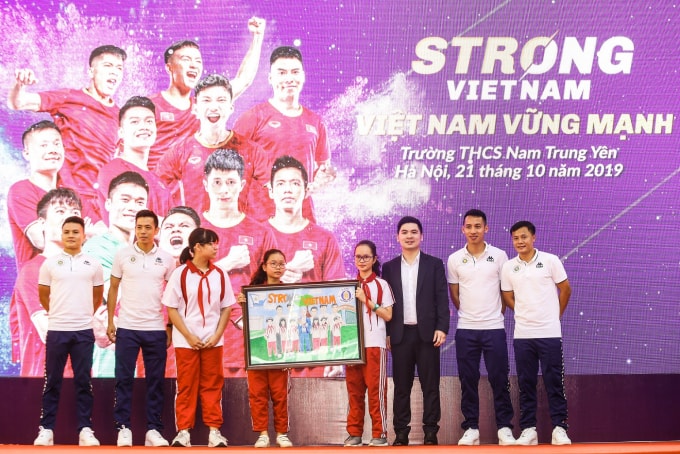Các cầu thủ CLB bóng đá Hà Nội và Trưởng Ban tổ chức chương trình “Strong Vietnam” Đỗ Vinh Quang nhận quà là bức tranh từ các em học sinh THCS Nam Trung Yên.