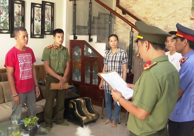 Cơ quan công an đọc quyết định khởi tố đối tượng Lê Hiếu (áo đỏ) về hành vi làm giả, sử dụng tài liệu giả của cơ quan, tổ chức.