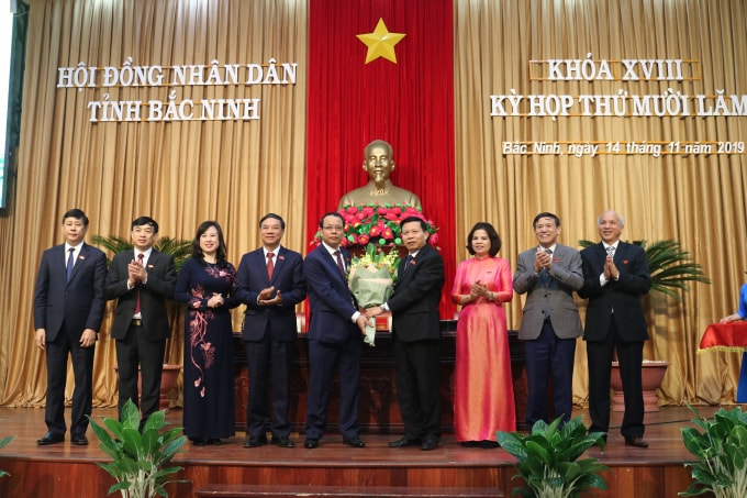 Ông Nguyễn Quốc Chung (người được tặng hoa bên trái) giữ chức Chủ tịch Hội đồng nhân dân.
