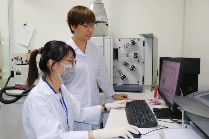Chị Thúy (người đứng) đang trao đổi với nhân viên trong phòng thí nghiệm của mình.