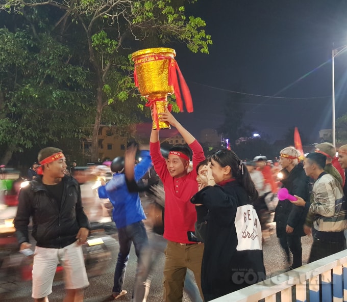 Một cổ động viên đã nâng cao chiếc cúp vô địch để hòa chung không khí náo nhiệt trên đường phố.
