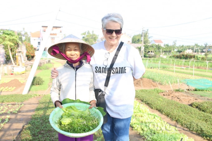 Cụ Xiêm chụp ảnh lưu niệm cùng du khách nước ngoài tham quan làng rau.
