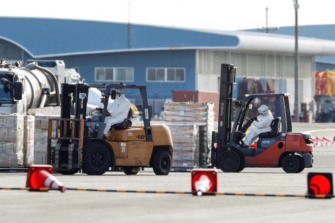 Các nhân viên vận chuyển nhu yếu phẩm cho những người bị cách ly trên tàu ở Yokohama, Nhật Bản. Ảnh: Reuters