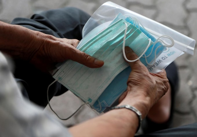 Một người đàn ông cầm khẩu trang tại Singapore. Ảnh: Reuters