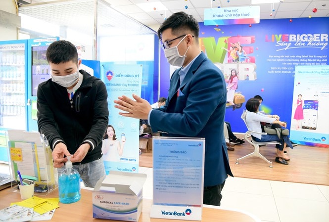 Cán bộ, nhân viên VietinBank hướng dẫn khách hàng sát khuẩn, đeo khẩu trang trước khi vào giao dịch