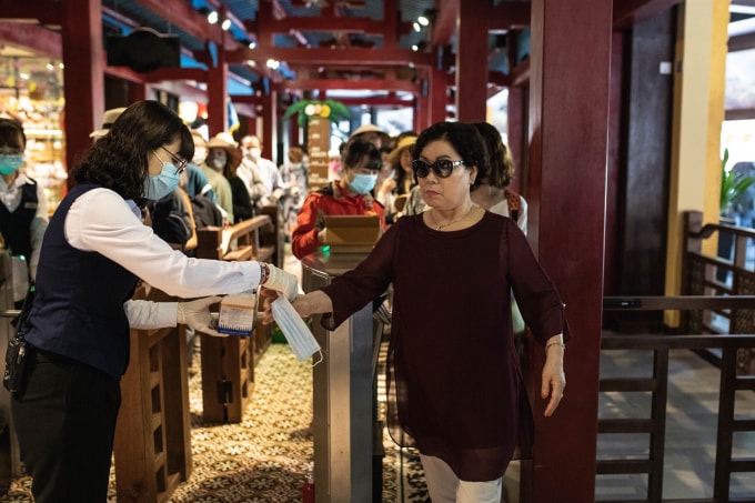 Nhân viên tại Bà Nà Hills phát khẩu trang miễn phí và hướng dẫn du khách đeo khẩu trang đúng cách.