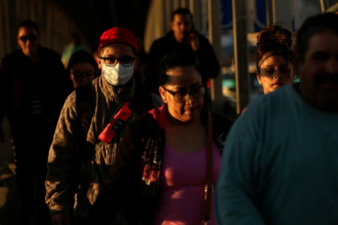 Một người đàn ông đeo khẩu trang đi qua cửa khẩu từ Mexico vào Mỹ. Ảnh: Reuters
