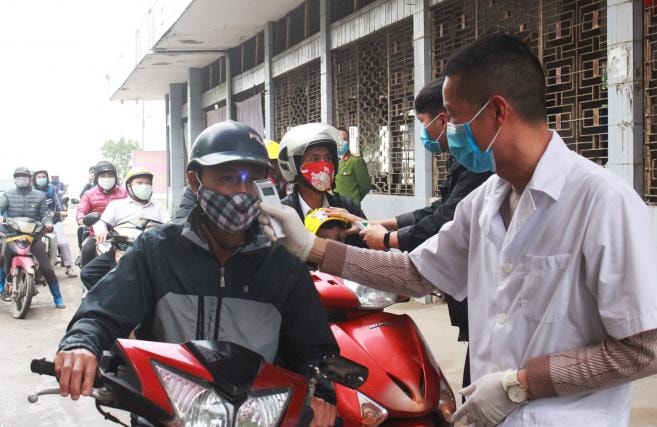 Kiểm tra thân nhiệt tại chốt phà Rừng. Ảnh: Đỗ Phương.