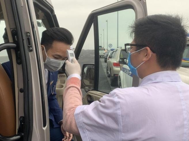 Kiểm tra thân nhiệt tất cả mọi trường hợp vào địa ban tỉnh tại chốt kiểm soát y tế cầu Bạch Đằng. Ảnh: Vũ Đức.