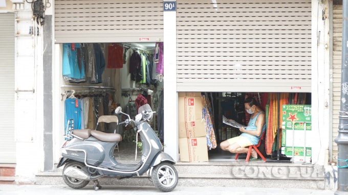 Một chủ cửa hàng trên phố Hàng Đào tranh thủ đọc báo. Ảnh H.Long.