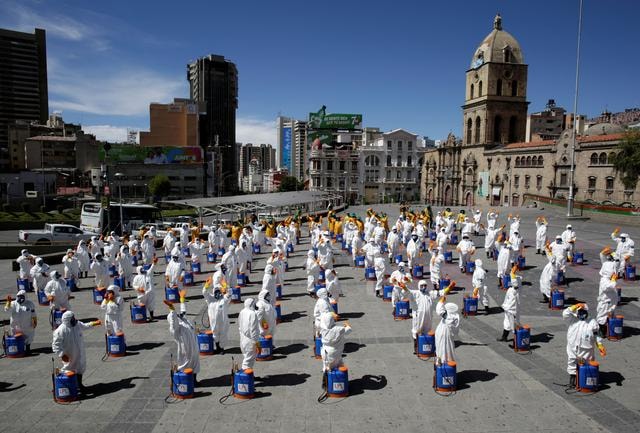 Các nhân viên y tế phun thuốc khử trùng tại thành phố La Paz, Bolivia. Ảnh: Reuters