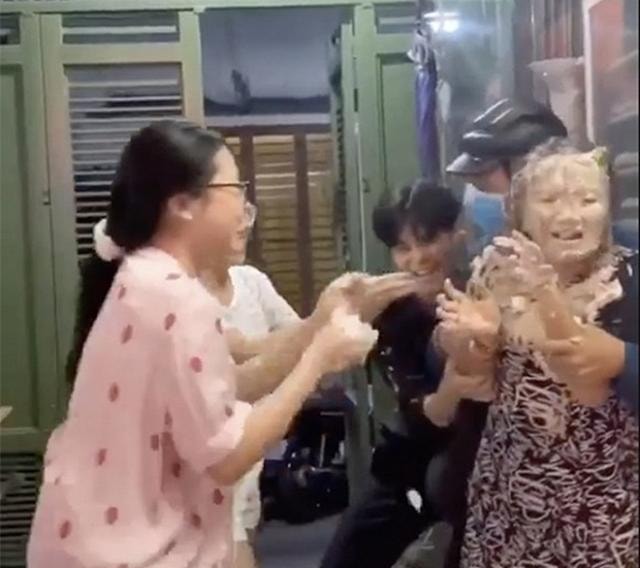 Hình ảnh cắt ra từ clip, Mỹ Chi đang cùng các anh chị em trong nhà giữ chặt tay mẹ để trét bánh kem lên mặt