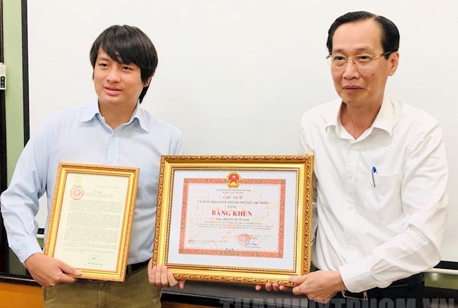 Thừa ủy quyền Phó Chủ tịch nước, Phó Chủ tịch Thường trực UBND thành phố Hồ Chí Minh Lê Thanh Liêm (bên phải) trao Thư khen cho anh Hoàng Tuấn Anh. Ảnh: HNM