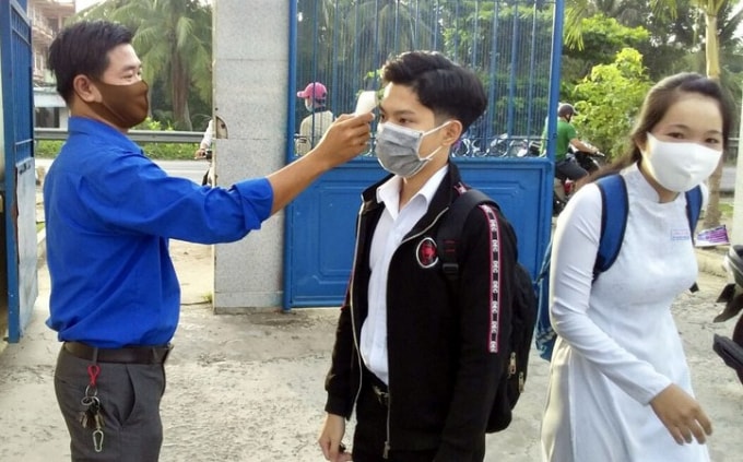 Kiểm tra thân nhiệt học sinh trước khi vào lớp. Ảnh: Tấn Phong - VOV ĐBSCL.