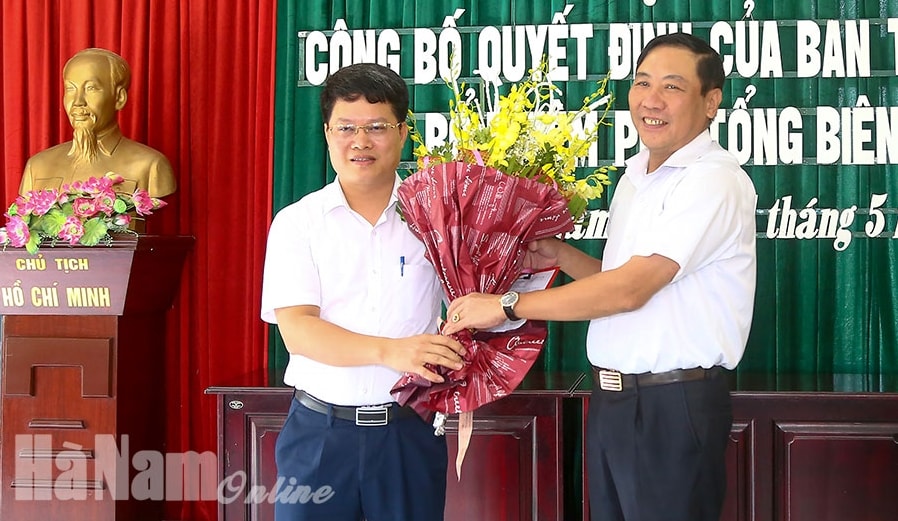 Ông Phạm Sỹ Lợi, Phó Bí thư Thường trực Tỉnh ủy, Chủ tịch HĐND tỉnh trao Quyết định và tặng hoa chúc mừng nhà báo Trần Ngọc Hưởng. Ảnh Thế Trang