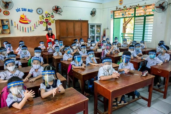 Học sinh đeo mũ chắn giọt bắn trong lớp học. Ảnh: Vietnamnet