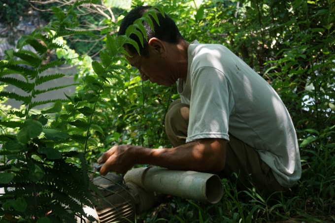 Ông Nguyễn Văn Bình bên chiếc máy bơm đã gần 1 tháng nay chưa thể sử dụng vì nước ô nhiễm nghiêm trọng.