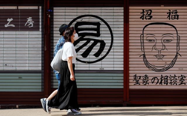 Hai người dân đi bộ ở Tokyo, Nhật Bản - Ảnh: Reuters