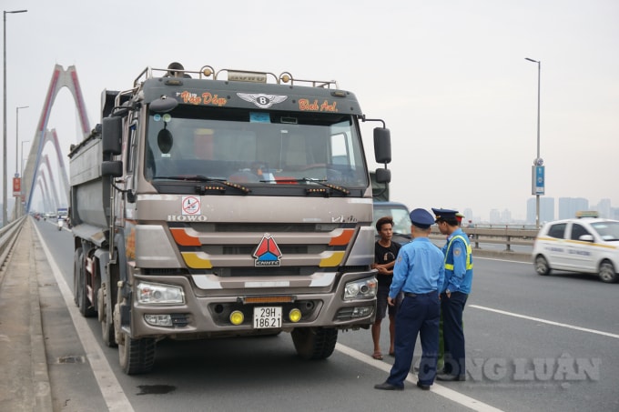 Lực lượng chức năng tiến hành kiểm tra hành chính yêu cầu lái xe không được dừng, đỗ xe trên cầu Nhật Tân. Đồng thời, đưa xe về chốt kiểm tra xử lý vi phạm. Ảnh H.Long.
