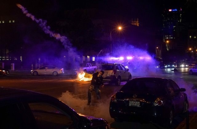 Một người biểu tình ném trả lựu đạn cay về phía cảnh sát ở Minneapolis. Ảnh: Reuters