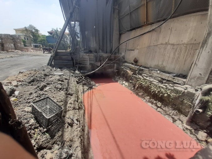 Dòng nước có màu đỏ chảy qua các kênh, mương dẫn xung quanh làng nghề giấy Phong Khê chảy trực tiếp ra sông Ngũ Huyện Khê. Ảnh H.Long.