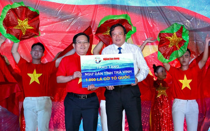 Ông Lê Văn Hẳn, Phó Chủ tịch UBND tỉnh Trà Vinh (bên phải), nhận bảng tượng trưng 1.000 lá cờ Tổ quốc do ông Tô Đình Tuân, Tổng Biên tập Báo Người Lao Động, trao tặng. Ảnh: Hoàng Triều
