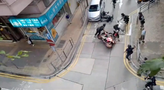 hình ảnh người đàn ông lao xe máy cầm biểu ngữ bị cảnh sát Hong Kong khống chế. Ảnh: MXH
