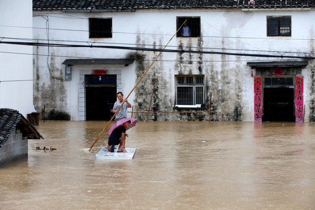 Người dân Trung Quốc di chuyển trên bè tự chế do lũ lụt ở tỉnh An Huy hôm 7/7 (Ảnh: Reuters).
