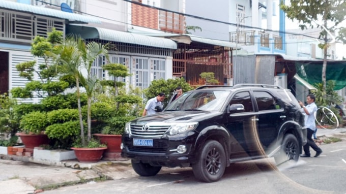 Lực lượng chức năng đưa người ra xe chuẩn bị rời khỏi nhà riêng của ông T. Ảnh: Châu Anh.