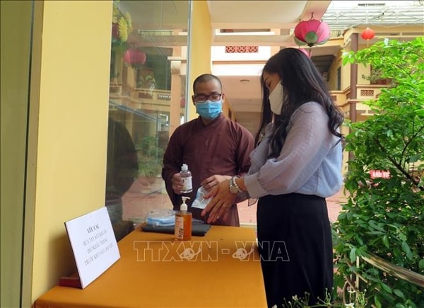Sư thầy chùa Anh Vinh (TP Tuyên Quang) hướng dẫn người dân thực hiện rửa tay trước khi vào lễ chùa. Ảnh: TTXVN