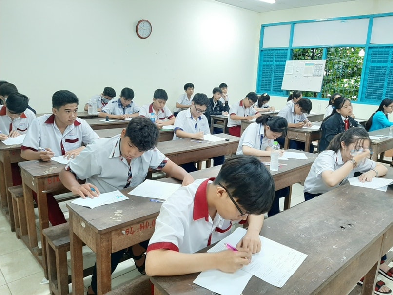 Thí sinh tập trung làm bài thi mặc ngoài trời vẫn đang mưa. Ảnh: internet.
