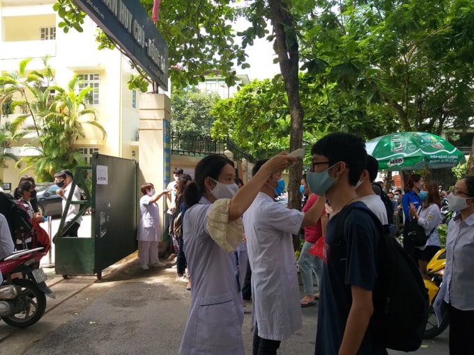 Các em được cán bộ y tế phụ trách điểm thi đo thân nhiệt một cách cẩn thận (ảnh Minh Triết).