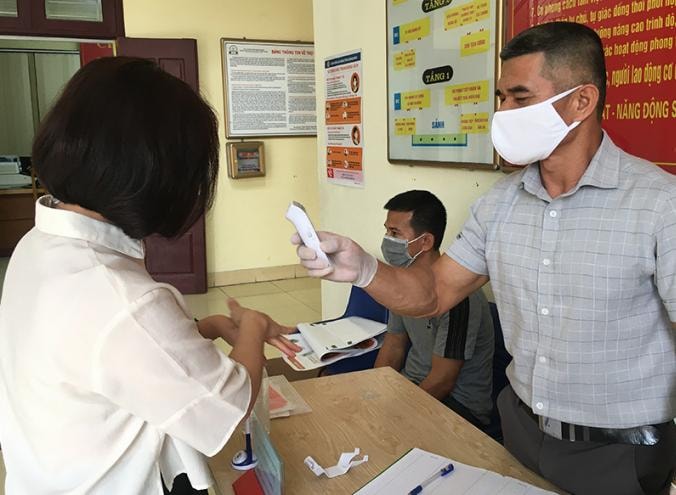 Kiểm tra thân nhiệt, sát khuẩn tay tất cả khách ra, vào trụ sở UBND phường Cẩm Thịnh, phòng chống dịch Covid-19. Ảnh: Cao Quỳnh.