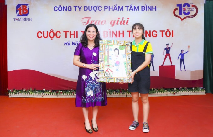 Dược sĩ Lê Thị Bình và bức tranh do cháu học sinh 13 tuổi vẽ trong cuộc thi “Tâm Bình trong tôi”.