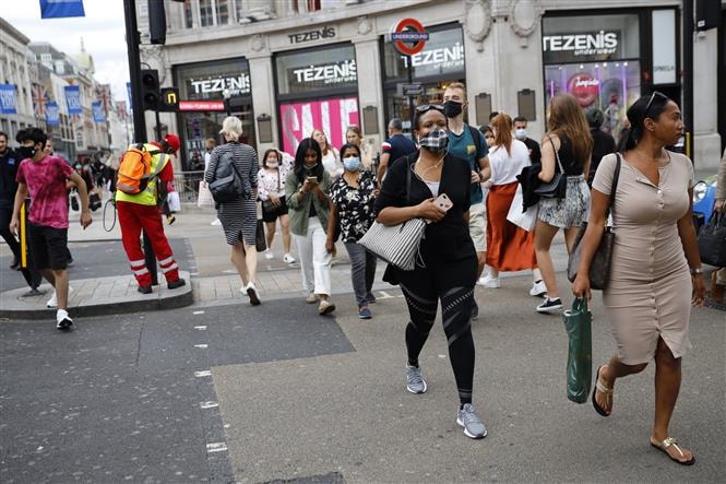 Người dân đeo khẩu trang phòng lây nhiễm COVID-19 khi di chuyển trên đường phố tại London, Anh ngày 24/7/2020. Ảnh: AFP/TTXVN.