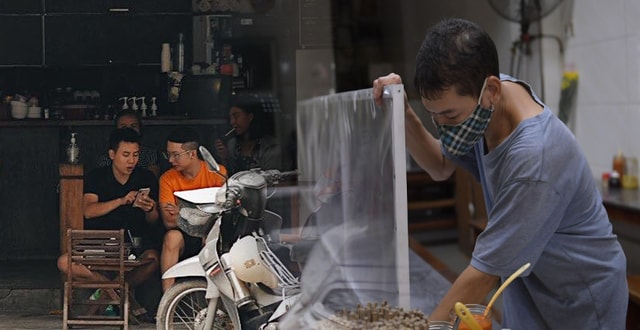 Người kinh doanh quán ăn ở Hà Nội lắp tấm kính chắn để phòng chống dịch Covid-19. Ảnh: TL.