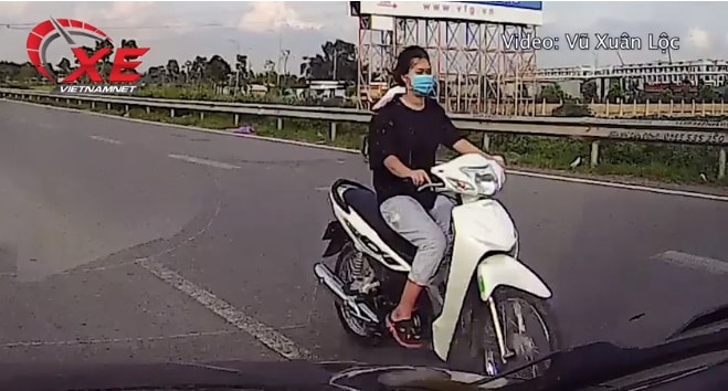 Cô gái trẻ đầu trần phóng xe máy ngược chiều trên cao tốc. Ảnh: Vũ Xuân Lộc.