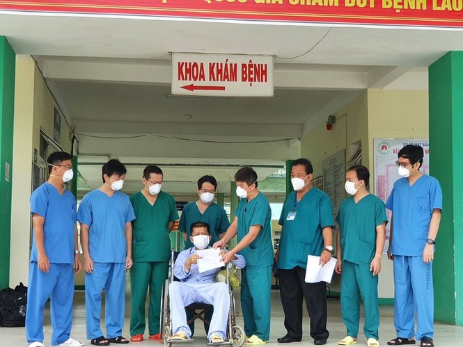 Các y bác sĩ Bệnh viện Phổi Đà Nẵng trao giấy tờ ra viện và chúc mừng bệnh nhân 582 khỏi COVID-19. Ảnh: TL.